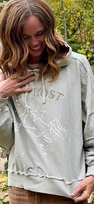 Close-up of the "Get Lost" embroidery and Kayla's inked mountains and star
