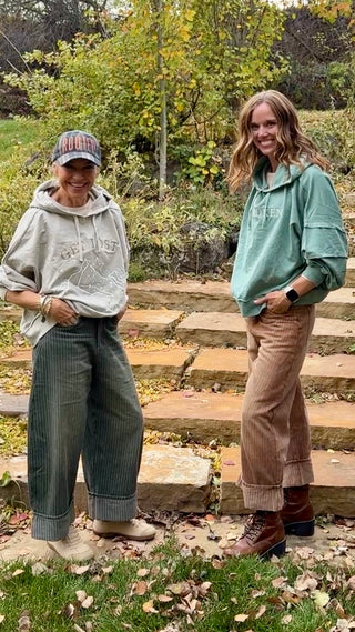 Two women in Off the Cuff barrel leg pants, Washed Olive and Washed Brown, standing on stone steps