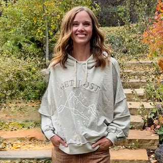 Women's Get Lost hoodie in Soft Stone warm gray, full front view with "Get Lost" embroidery and mountain art