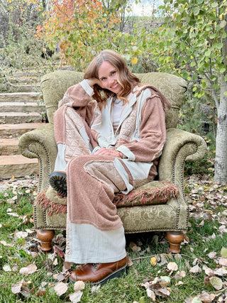 Woman smiling in a vintage green armchair wearing the Peaceful Easy Feelin' patchwork hoodie and jogger set
